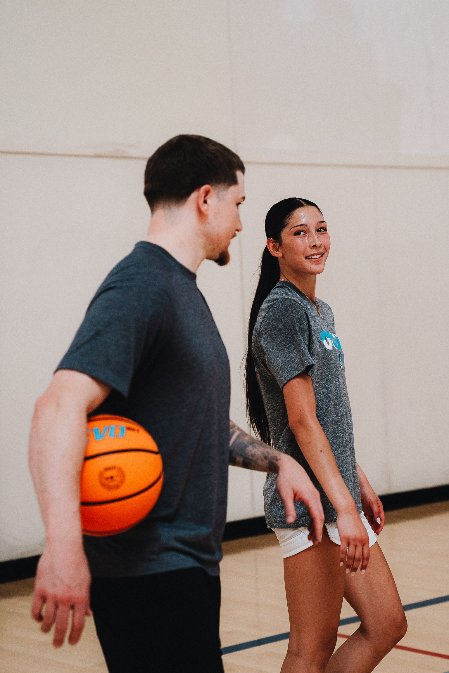 basImage of basketball player Estella Guido looking back at her coach who is holdin an evo basketball under his arms